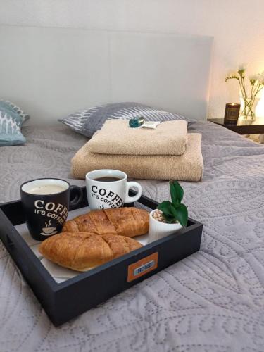a tray with some pastries and cups of coffee on a bed at Apartamenty Akacjowa Villa106 in Nędza
