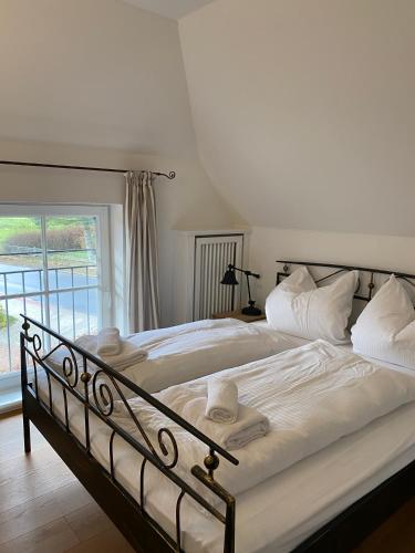 a bedroom with a bed with white sheets and a window at HofGut Bockelkathen Apartment 3 in Lüdersburg