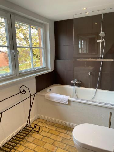 a bathroom with a tub and a toilet and a sink at HofGut Bockelkathen Apartment 3 in Lüdersburg