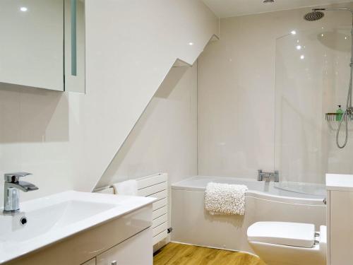 a white bathroom with a sink and a bath tub at Seascape Cottage in Allonby