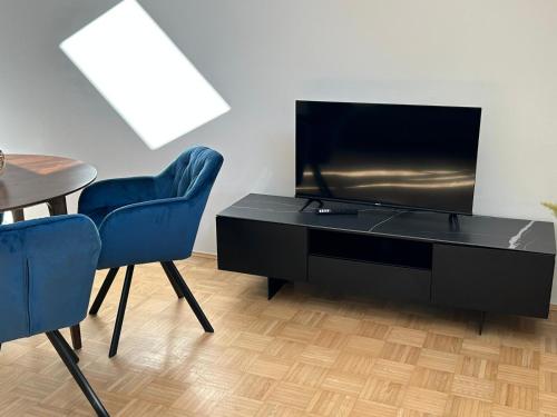a living room with two blue chairs and a television at Gamlitz - RaStra Top 20 in Gamlitz