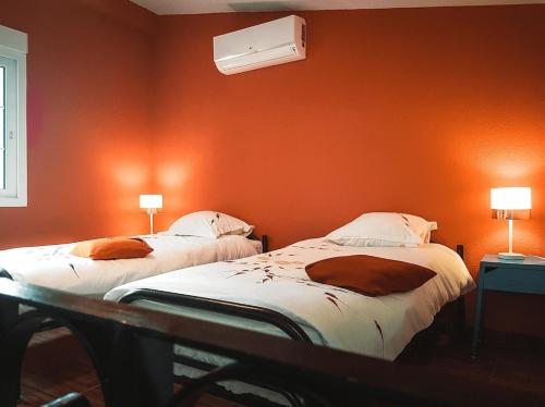 two beds in a room with an orange wall at Casa Cosy in Serra