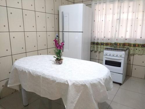 a white kitchen with a table with a white refrigerator at Casa Morumbi Foz do Iguaçu in Foz do Iguaçu