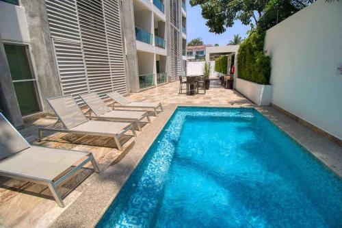a swimming pool with lounge chairs next to a building at 2 bd Loft in Versalles, Walk to the Beach! in Puerto Vallarta