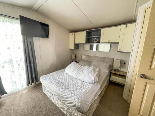 a bedroom with a bed with white sheets and a window at Modern 6 Berth Caravan For Hire At Fantasy Island In Skegness Ref 58009d in Skegness