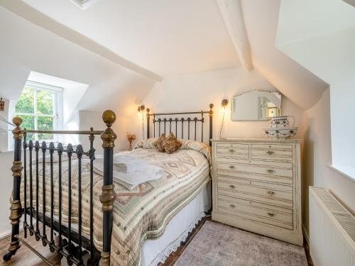 a bedroom with a bed with a dresser and a mirror at Church House Cottage in East Stour