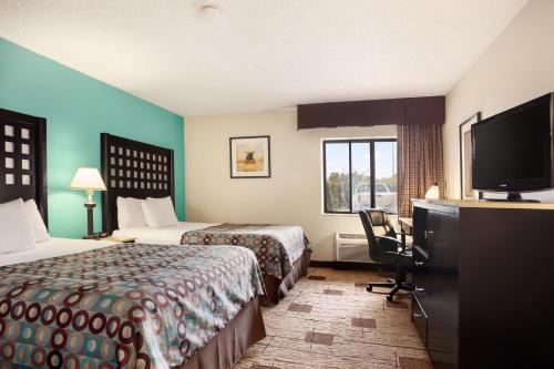 a hotel room with two beds and a flat screen tv at Days Inn by Wyndham Fort Smith in Fort Smith