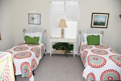 2 bedden in een kamer met groene kussens bij Island Sunshine in Dauphin Island