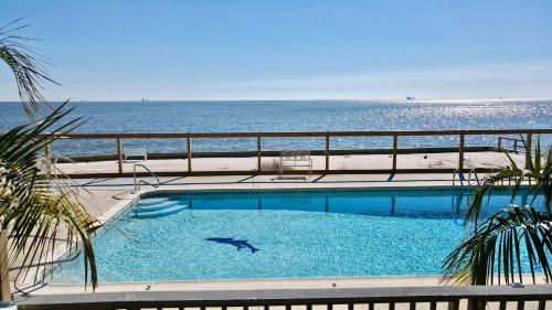 a swimming pool with the ocean in the background at Sandcastle 6B in Dauphin Island