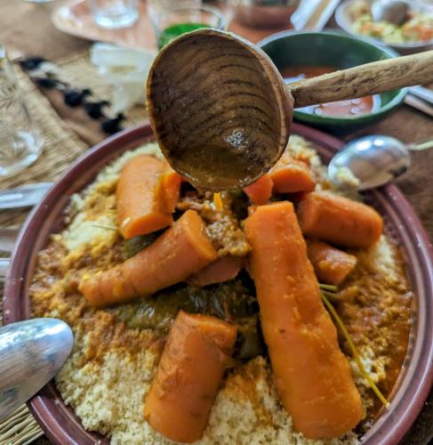 a bowl of food with carrots and a wooden spoon at Ecolodge du Draa in Ouled Otmane