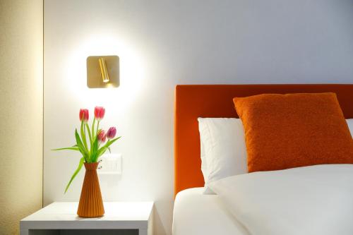 a vase of flowers on a table next to a bed at Boutique Hotel Piazza Grande in Locarno