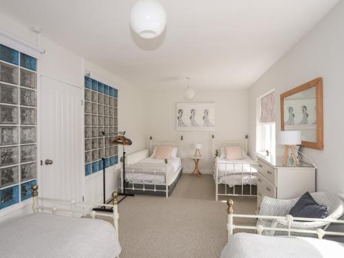 a white room with two beds and a couch at Nyth Y Fran in Abersoch