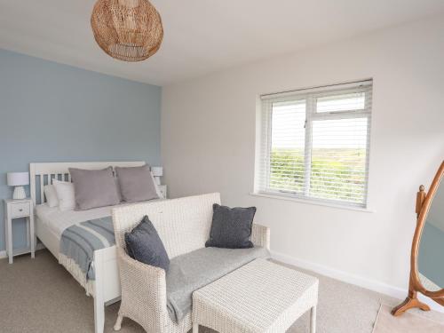 a bedroom with a bed and a chair and a window at Nyth Y Fran in Abersoch