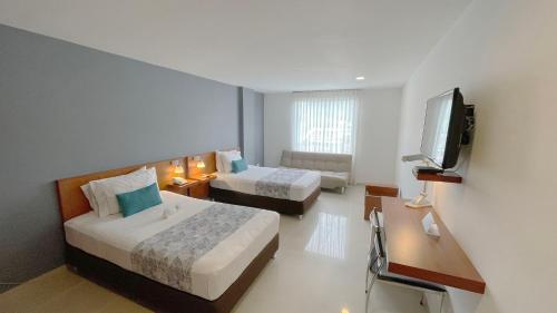 ein Hotelzimmer mit 2 Betten und einem Flachbild-TV in der Unterkunft Hotel MS Chipichape Plus in Cali