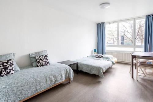 1 dormitorio con 2 camas, mesa y ventana en La villette ; super Studio privé Joli Spacieux; La Multiculture, en Aubervilliers