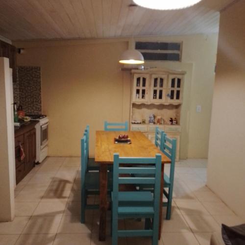 cocina con mesa de madera y sillas azules en Casa hasta 5 personas en Gualeguaychú