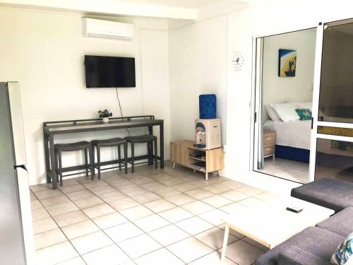 a living room with a couch and a tv on the wall at Avarua Escape, Rarotonga in Avarua
