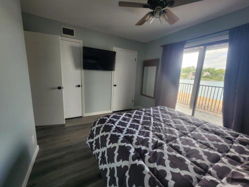 a bedroom with a bed and a television and a balcony at Lakefront condo with a VIEW Osage Beach in Osage Beach