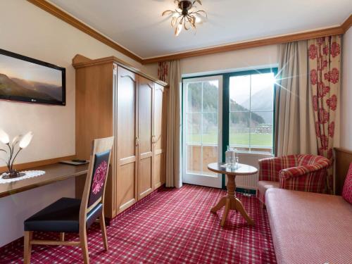 um quarto de hotel com um sofá, uma mesa e uma janela em Ferienhof Oblasser em Mayrhofen