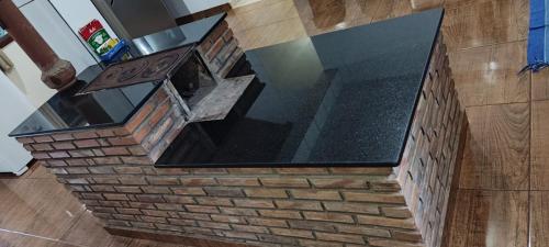 an island in a kitchen with a brick wall at Casa do Vani - Lapinha da Serra in Santana do Riacho
