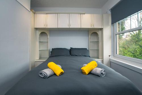 - une chambre avec un grand lit et 2 oreillers jaunes dans l'établissement Cosy & Central 2BD Apartment Milngavie, Glasgow, à Milngavie