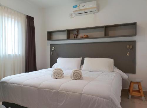 um quarto com uma cama branca com duas toalhas em - Puna - Depto para 4- Nuevo y comodo a 5 min del centro em Salta