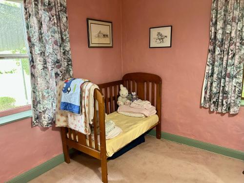 a baby crib in a room with pink walls at Woodvale at Cooma in Cooma