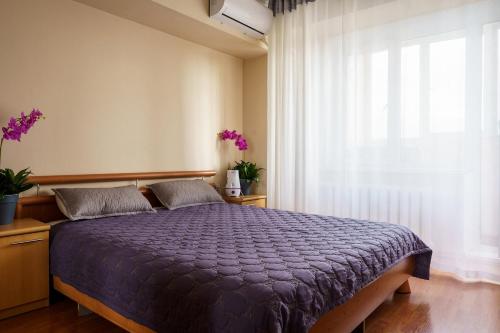 a bedroom with a bed with a purple comforter and a window at Золотой квадрат 60 кв2 in Almaty