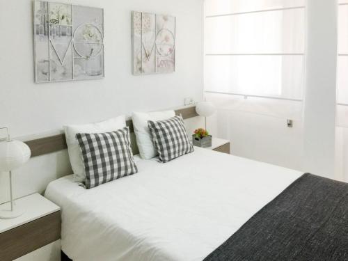1 dormitorio blanco con 1 cama grande y 2 almohadas en COSY FLATS 1ª LINEA VISTAS ESPECTACULARES, en Alicante