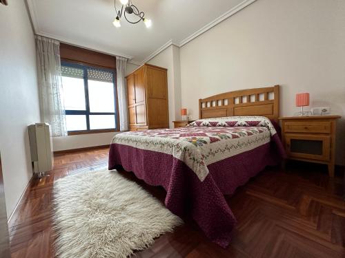 een slaapkamer met een bed, een raam en een tapijt bij Apartamento Salgueirón in Cangas de Morrazo