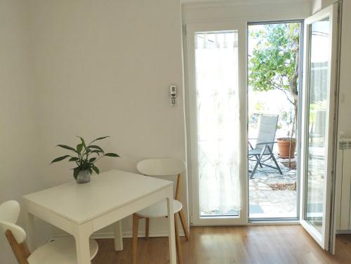 a white table and chairs in a room with a patio at Active Apartments Koper in Koper