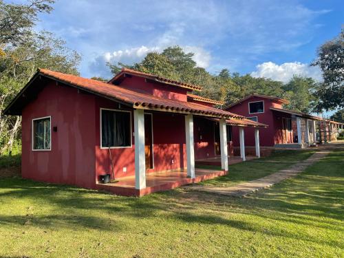 a red house with a porch in the grass at Chalés do Recanto in São João del Rei