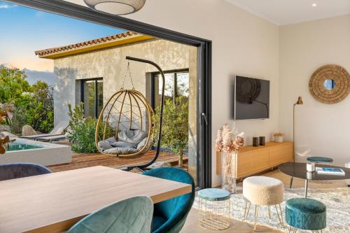 - un salon avec une table, des chaises et une balançoire dans l'établissement Villa Nivalaggia avec piscine à 15-20min de Porto-Vecchio et de Bonifacio, sunsets sur les champs, à Figari