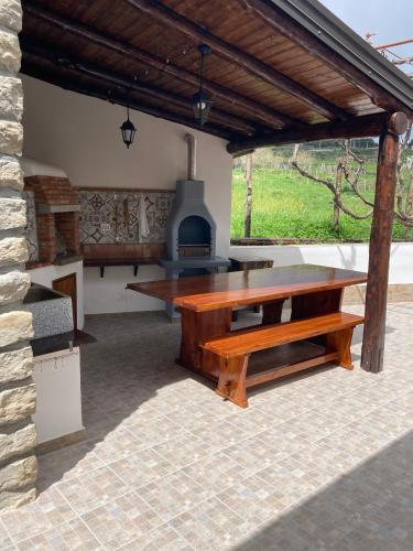 a patio with a wooden table and a stove at B&B Tenuta Piano Campo in Ucria