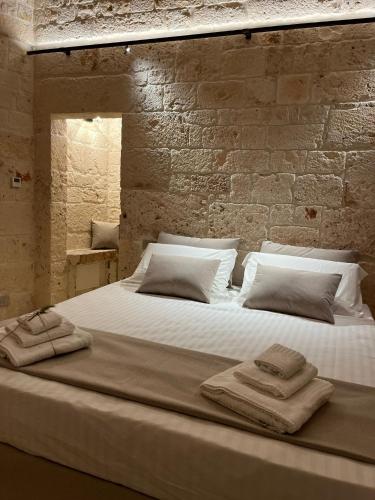 ein großes weißes Bett mit Handtüchern darüber in der Unterkunft BORGANTHIA - IL CHIOSTRO DEI MEDICI in Alberobello