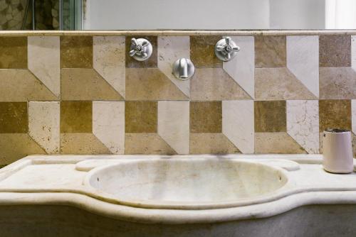 a stone sink in a bathroom with a checkered wall at La Casetta Nel Borgo in Castelnuovo di Val di Cecina