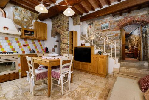 una cucina con tavolo, sedie e parete in pietra di La Casetta Nel Borgo a Castelnuovo di Val di Cecina