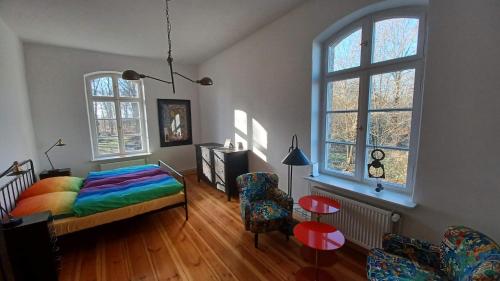 a bedroom with a bed and a chair and windows at "Parkwohnung" im Kunstgut Krahne in Krahne