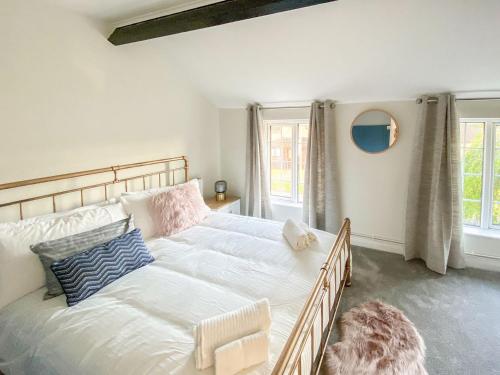 a bedroom with a large white bed with pillows at Lords Cottage in Coleford