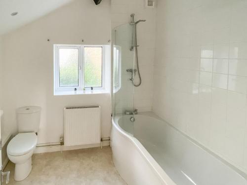 La salle de bains blanche est pourvue d'une baignoire et de toilettes. dans l'établissement Lords Cottage, à Coleford