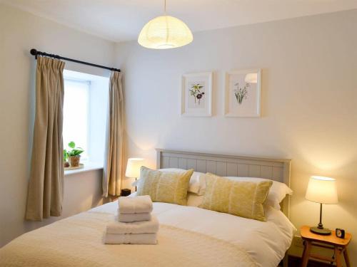 een slaapkamer met een bed met gele kussens en een raam bij Wheatsheaf Cottage - 80021 in Sawdon
