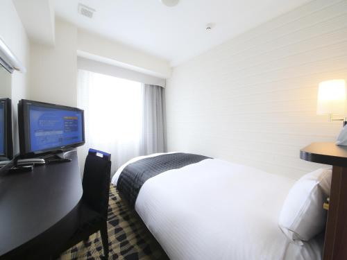 東京にあるアパホテル〈築地駅南〉のベッド1台、薄型テレビが備わるホテルルームです。