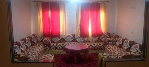 uma sala de estar com um sofá e cortinas vermelhas em شقة العتماني للكراء اليومي em Rissani