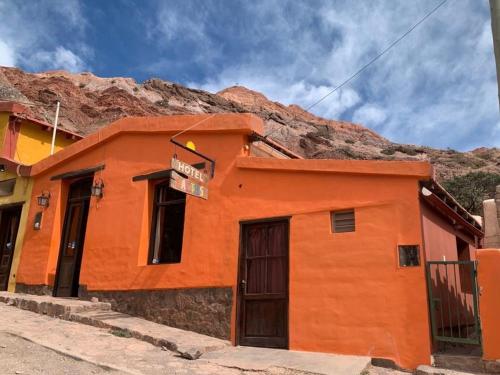 pomarańczowy budynek przed górą w obiekcie Hotel Cactus Cerro w mieście Purmamarca