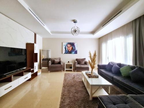 een woonkamer met een bank en een tv bij Axxodia Cairo Festival Residence in Caïro