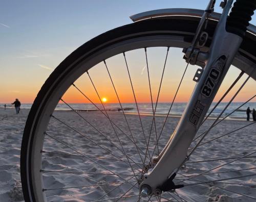 una bicicletta parcheggiata sulla spiaggia al tramonto di Baltica Mielenko - domki apartamentowe nad morzem a Mielenko