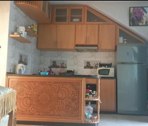 - une cuisine avec des placards en bois et un réfrigérateur dans l'établissement DREAM LIND SAHEL, à Zemmour Touirza