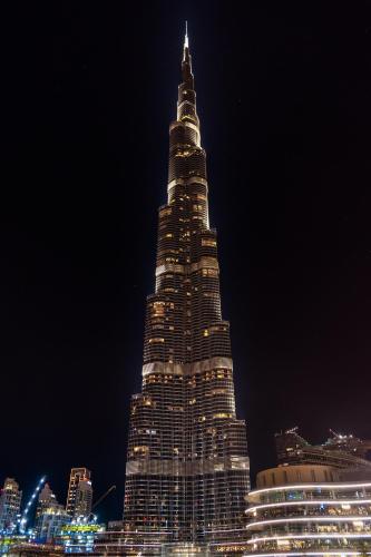 a tall building is lit up at night at Jumera in Dubai
