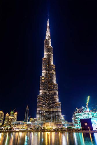 a tall building with lights on it at night at Jumera in Dubai
