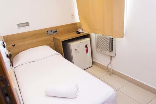 a small room with a bed and a small refrigerator at Minuano Hotel Home próximo ao aeroporto in Porto Alegre
